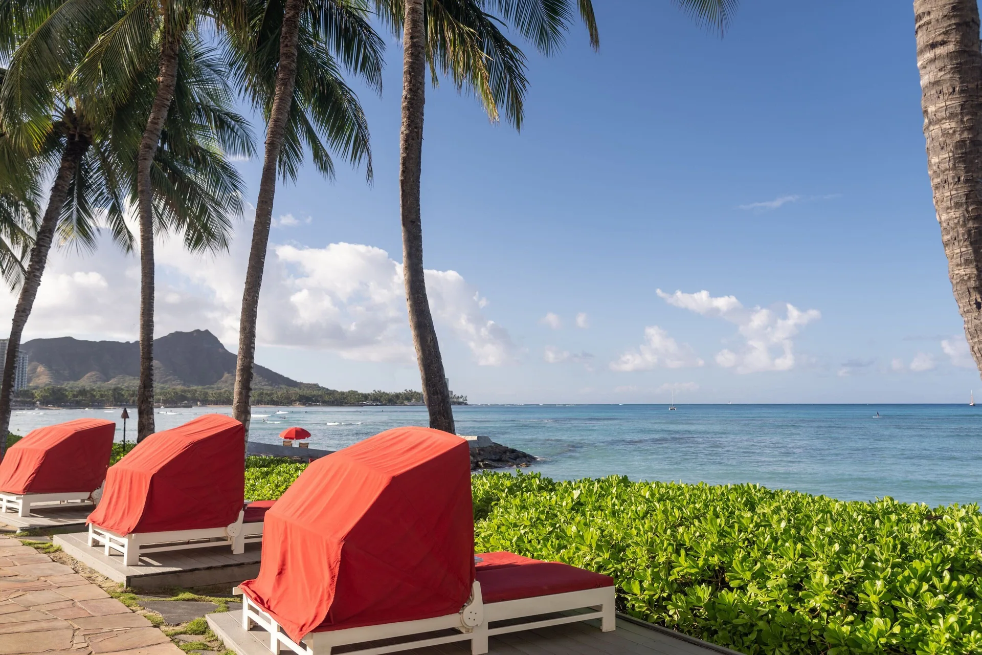 Red pool loungers facing the ocean and Diamond Head at Sheraton Waikiki Beach Resort.