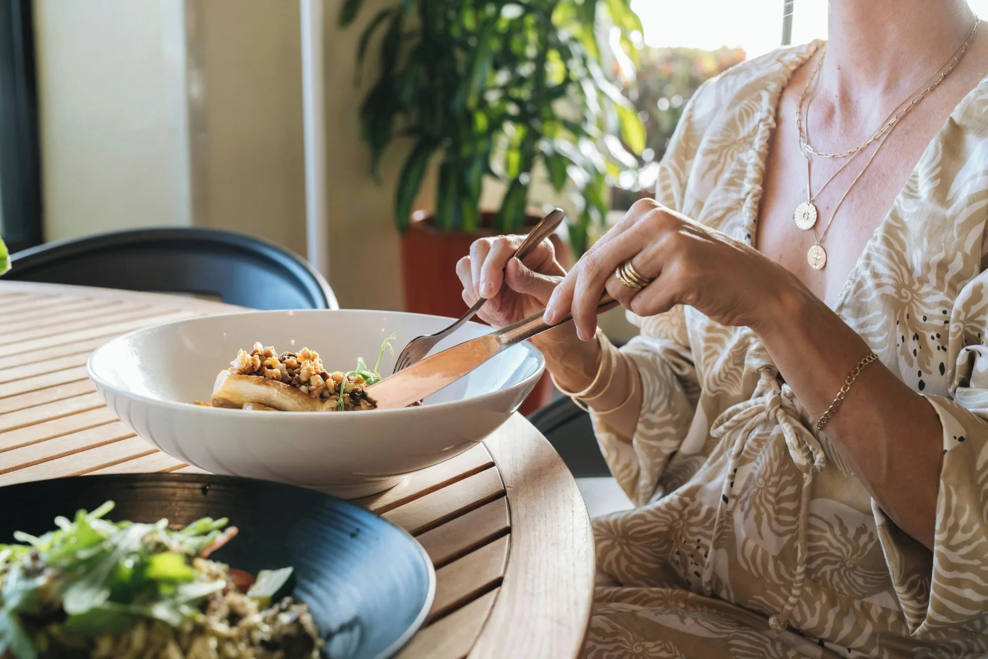 Guest dining at a wood table with plated dishes at Sheraton Waikiki Beach Resort.