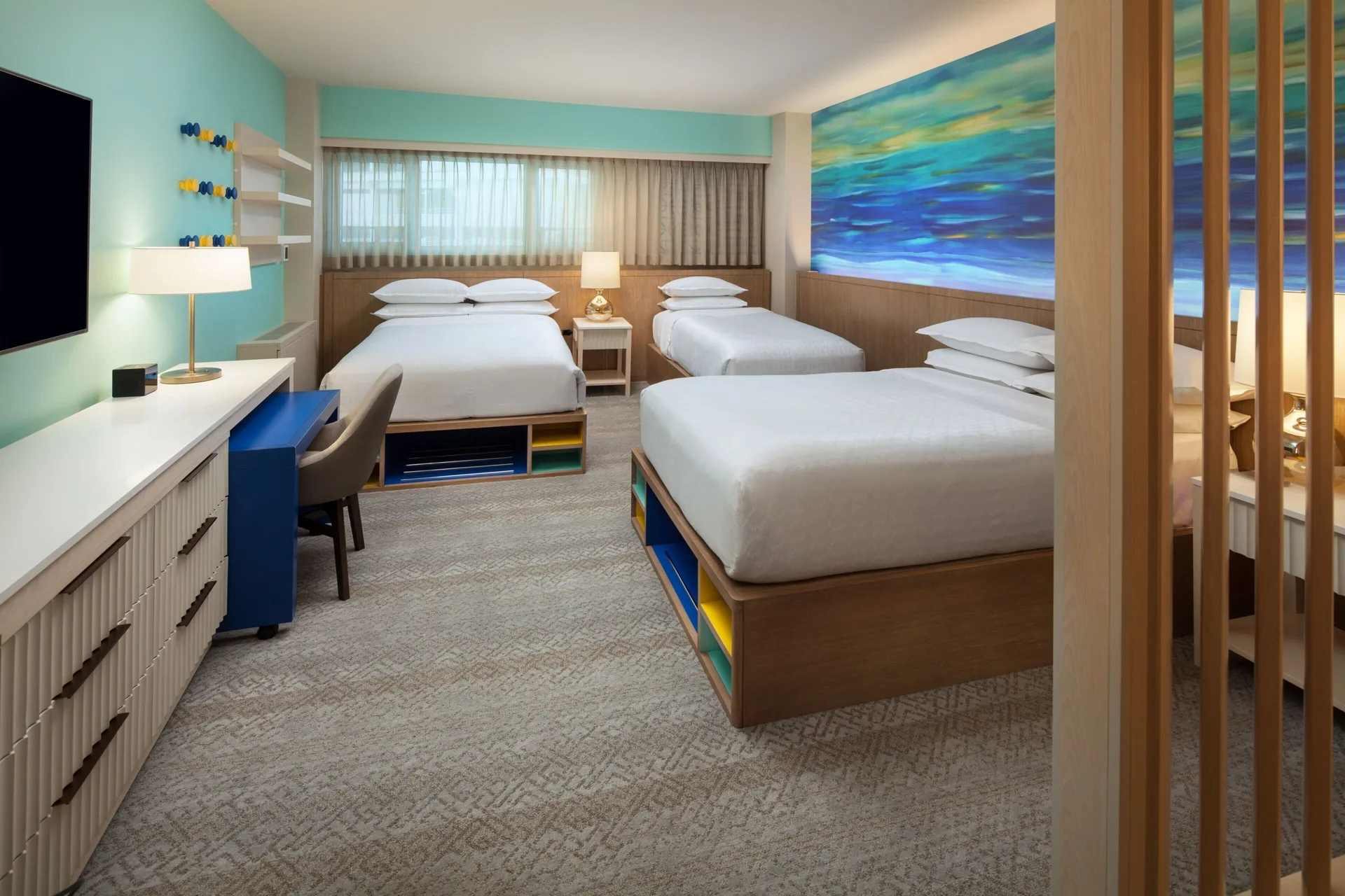 Family Room with multiple beds, desk, and ocean-inspired wall art at Sheraton Waikiki Beach Resort.