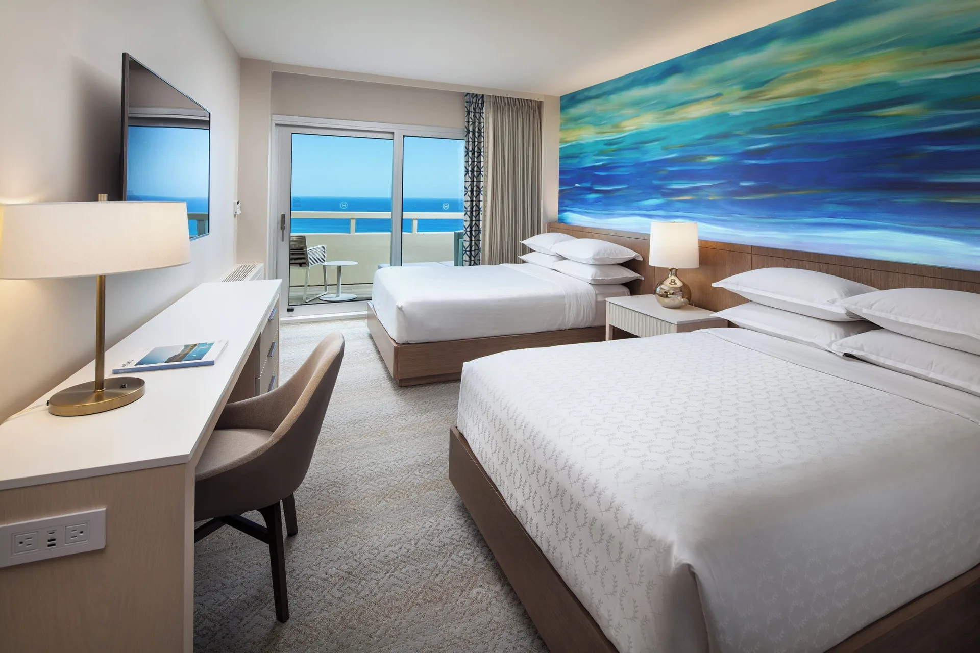 Oceanfront guest room with two beds and balcony at Sheraton Waikiki Beach Resort.