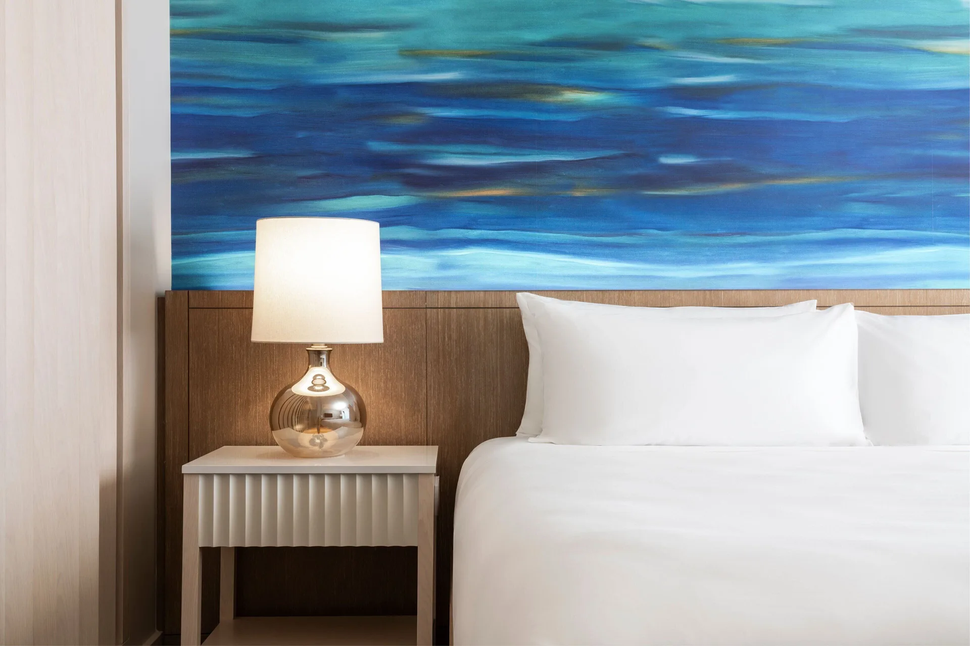 Oceanfront room bed with blue wall art at Sheraton Waikiki Beach Resort.