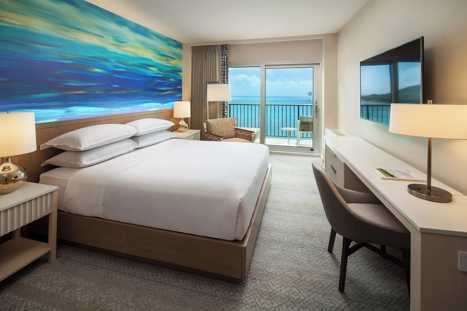 King bed oceanfront room with balcony doors at Sheraton Waikiki Beach Resort.