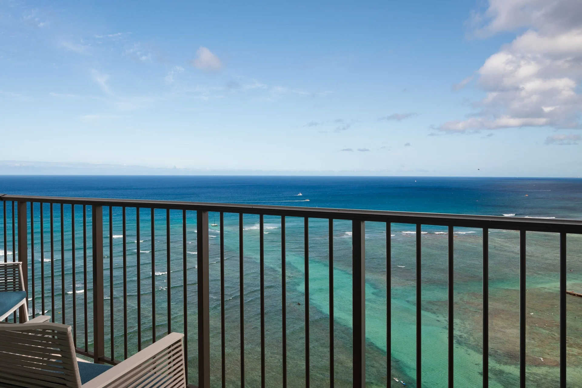Oceanfront balcony with lounge chairs at Sheraton Waikiki Beach Resort overlooking turquoise water.