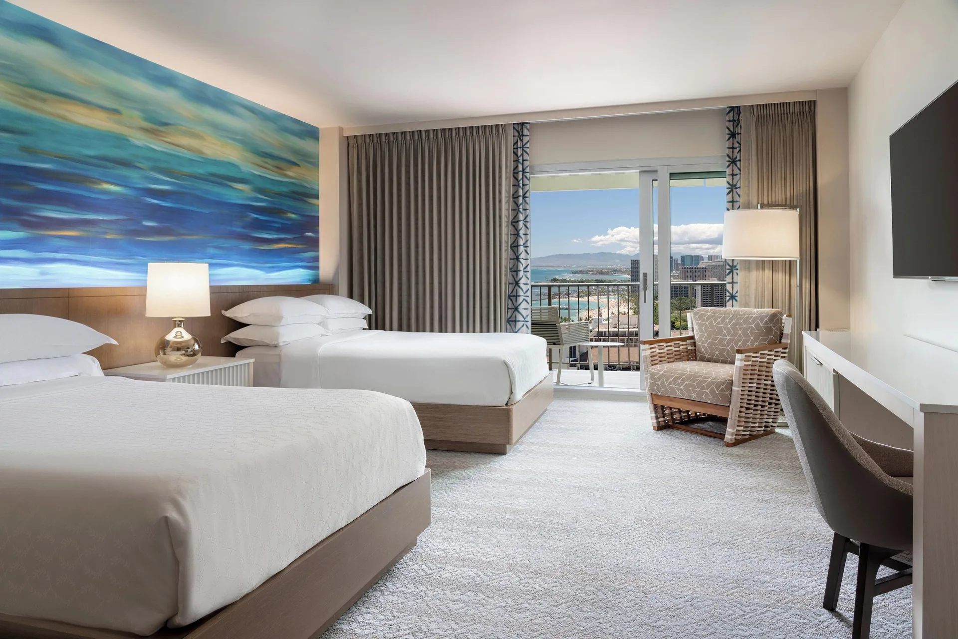 Two-bed guest room with balcony view at Sheraton Waikiki Beach Resort.
