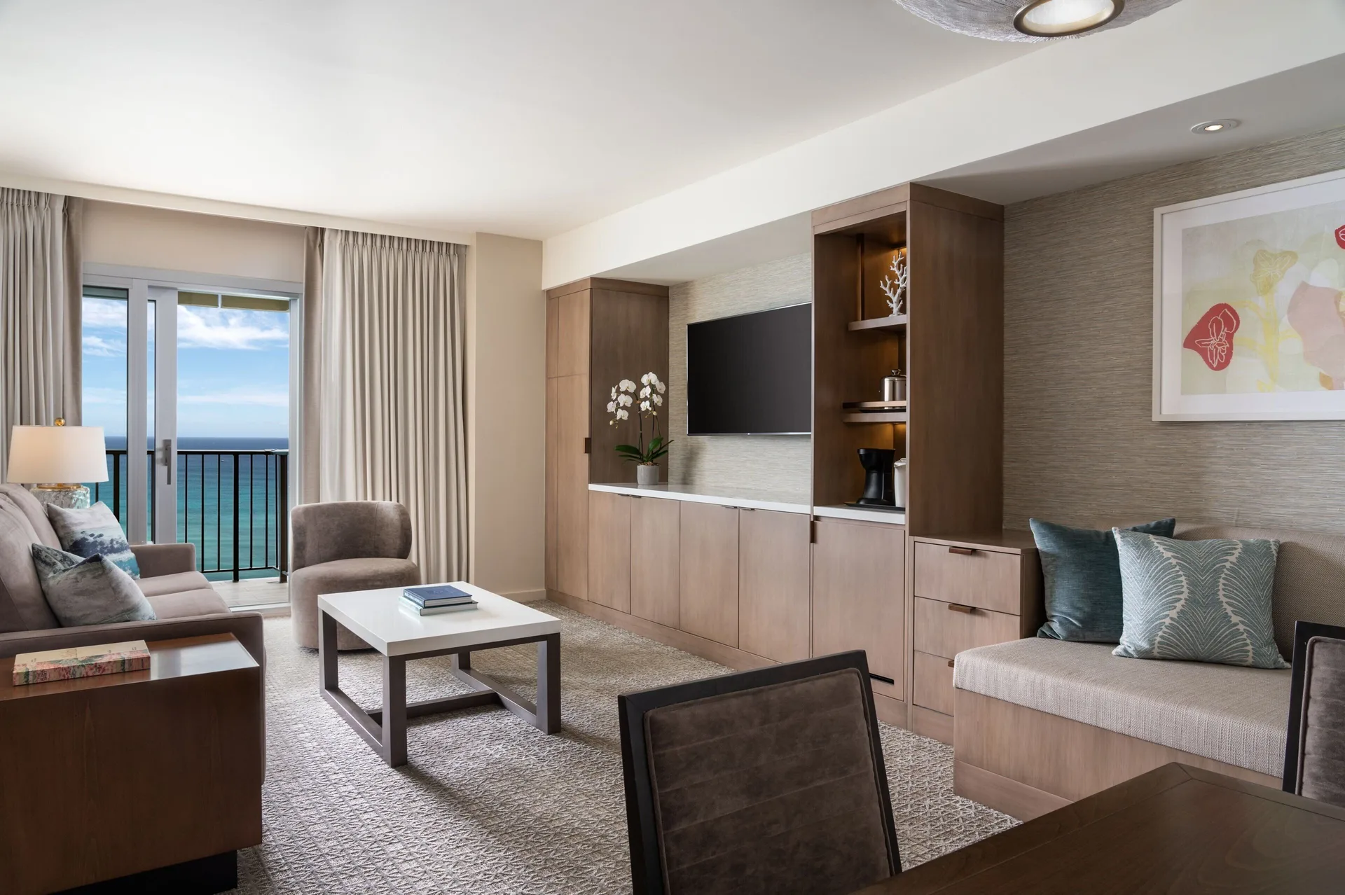 Ohana Suite living room at Sheraton Waikiki Beach Resort with ocean balcony, sofa, TV, and dining area.
