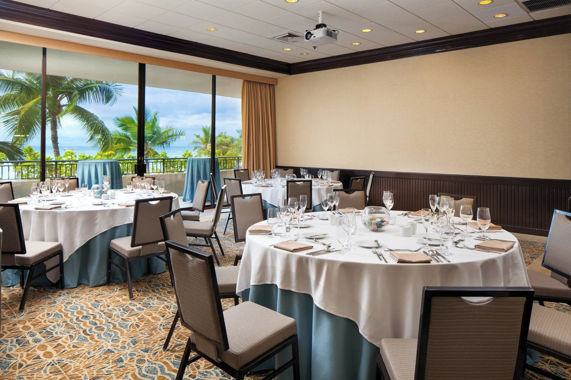 Banquet room with round dining tables and palm views at Sheraton Waikiki Beach Resort.