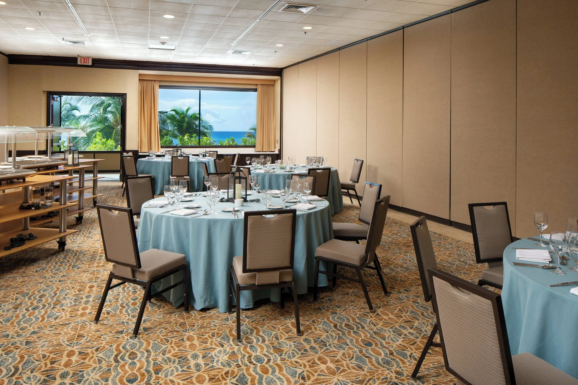 Event room with round tables, buffet station, and ocean-facing windows at Sheraton Waikiki Beach Resort.