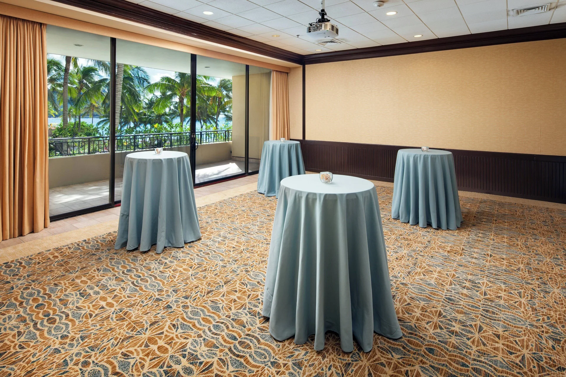 Event room at Sheraton Waikiki Beach Resort with cocktail tables and balcony views of palms and ocean.