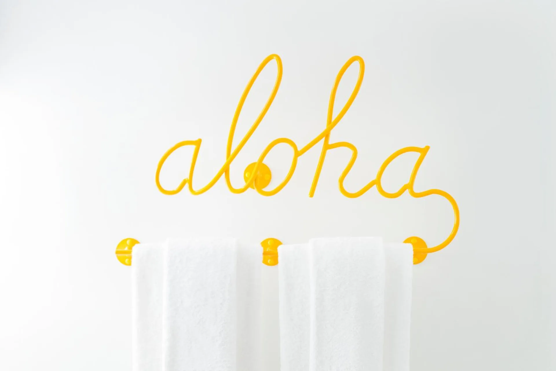 Yellow aloha towel rack with white towels at Shoreline Hotel Waikiki.