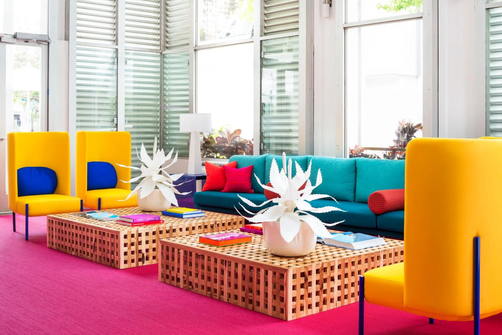 Bright lobby lounge with teal sofa and yellow chairs at Shoreline Hotel Waikiki.