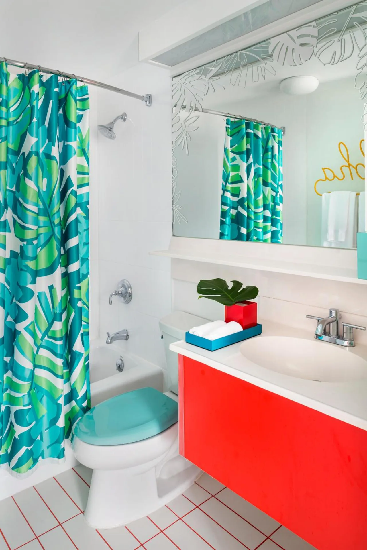 Guest bathroom with red vanity and tropical shower curtain at Shoreline Hotel Waikiki.