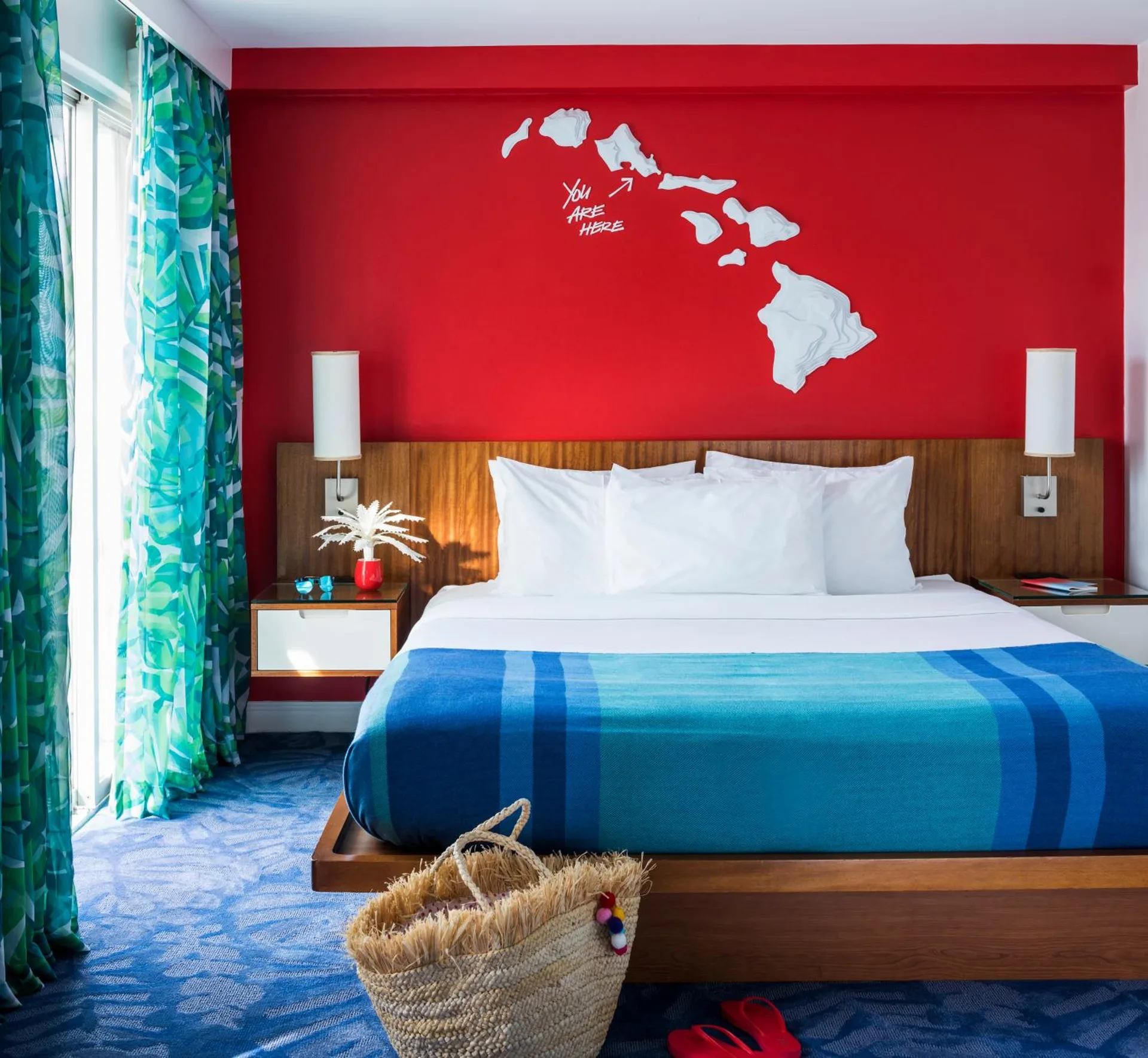 Guest room with king bed, red accent wall and island map art at Shoreline Hotel Waikiki.