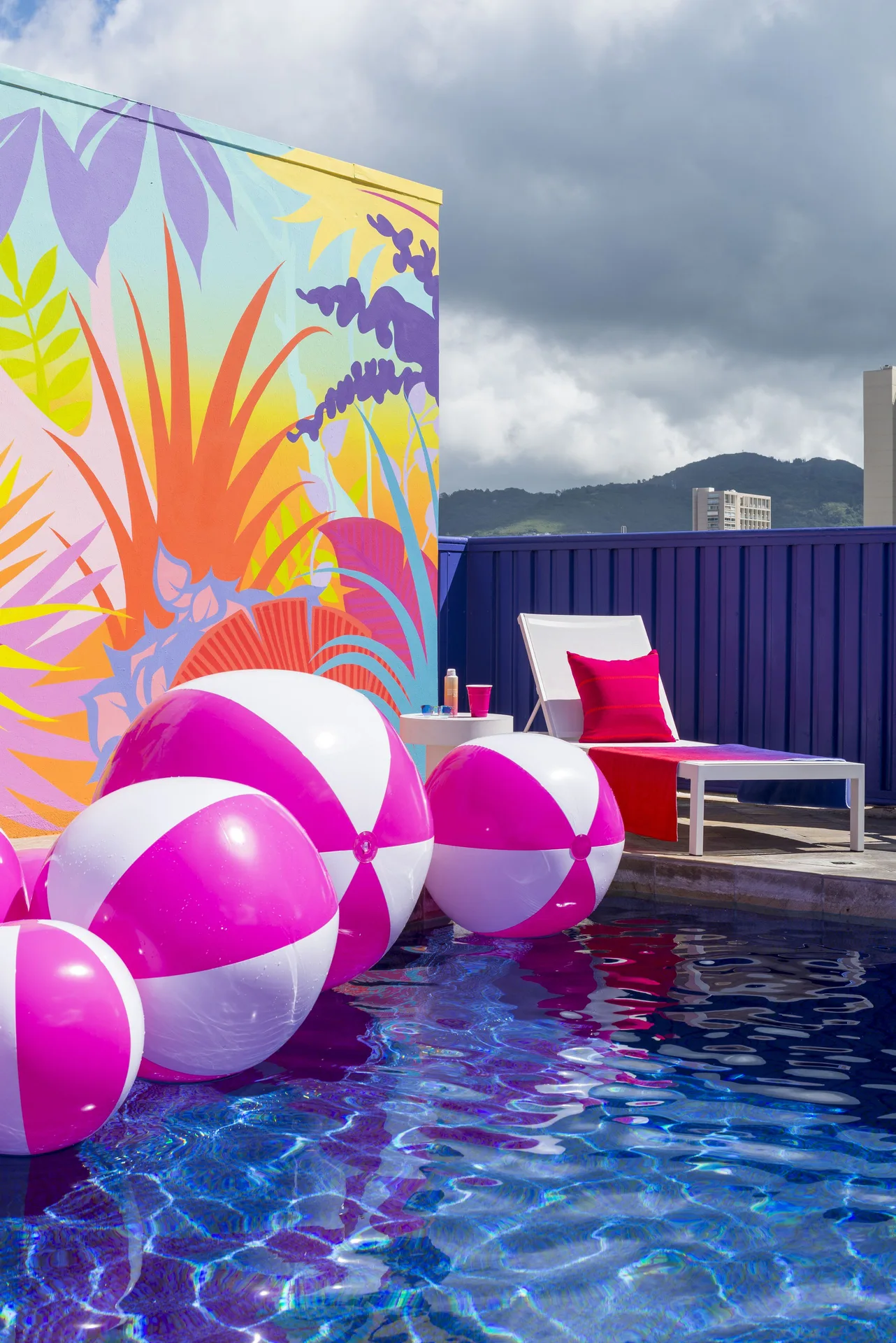 Pink beach balls floating by a pool lounger at Shoreline Hotel Waikiki.