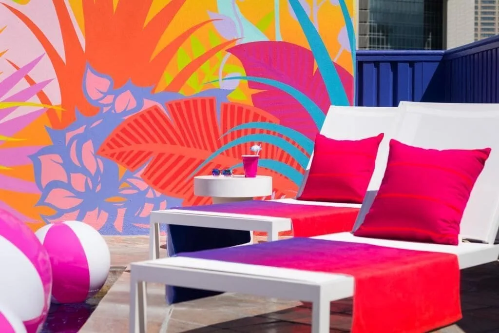 Poolside lounge chairs with pink cushions and a tropical mural at Shoreline Hotel Waikiki.