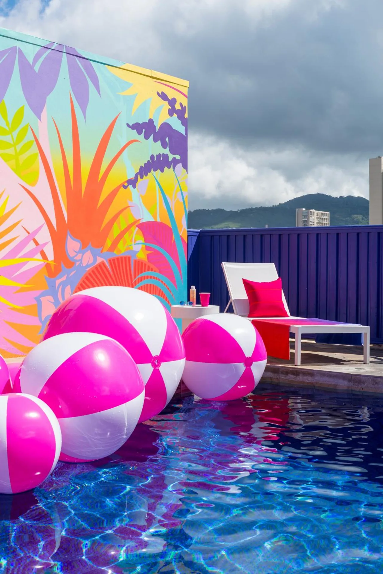 Rooftop pool with pink beach balls and a colorful mural at Shoreline Hotel Waikiki.