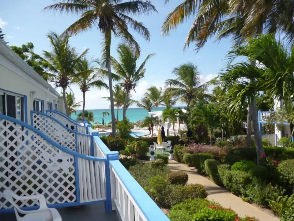 Balcony view over gardens, palms and turquoise water at Sibonné Beach Hotel.