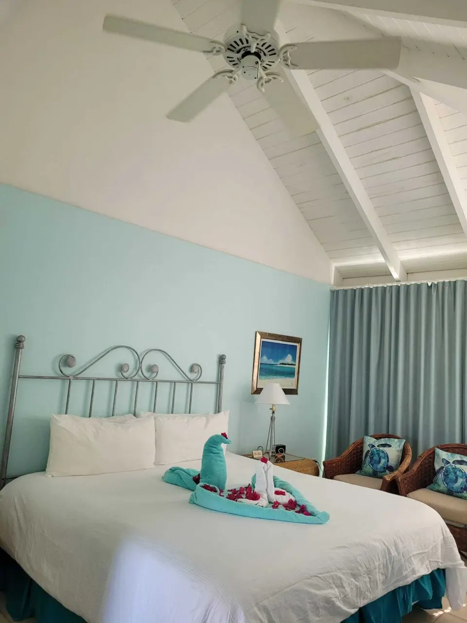 Balcony Room king bed with towel swans and vaulted ceiling at Sibonné Beach Hotel.