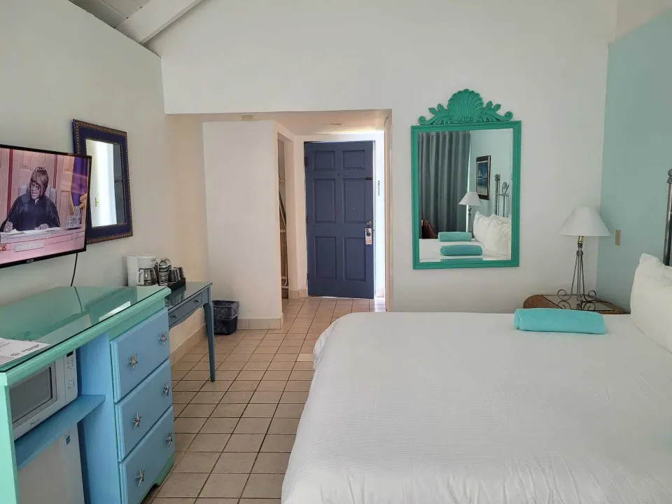 Balcony Room with king bed, turquoise dresser and wall mirror at Sibonné Beach Hotel.