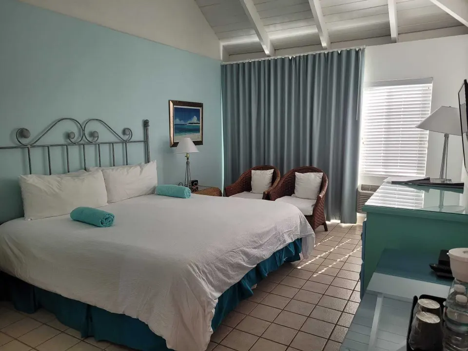 Balcony Room with king bed, wicker chairs and turquoise accents at Sibonné Beach Hotel.