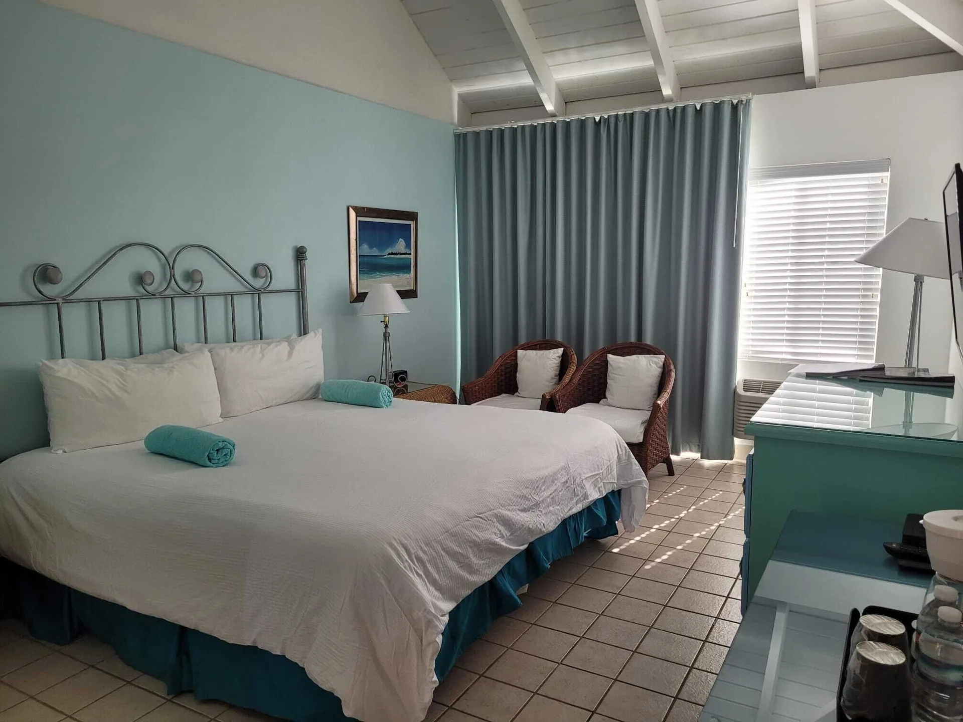 Balcony Room with king bed, wicker chairs and turquoise accents at Sibonné Beach Hotel.