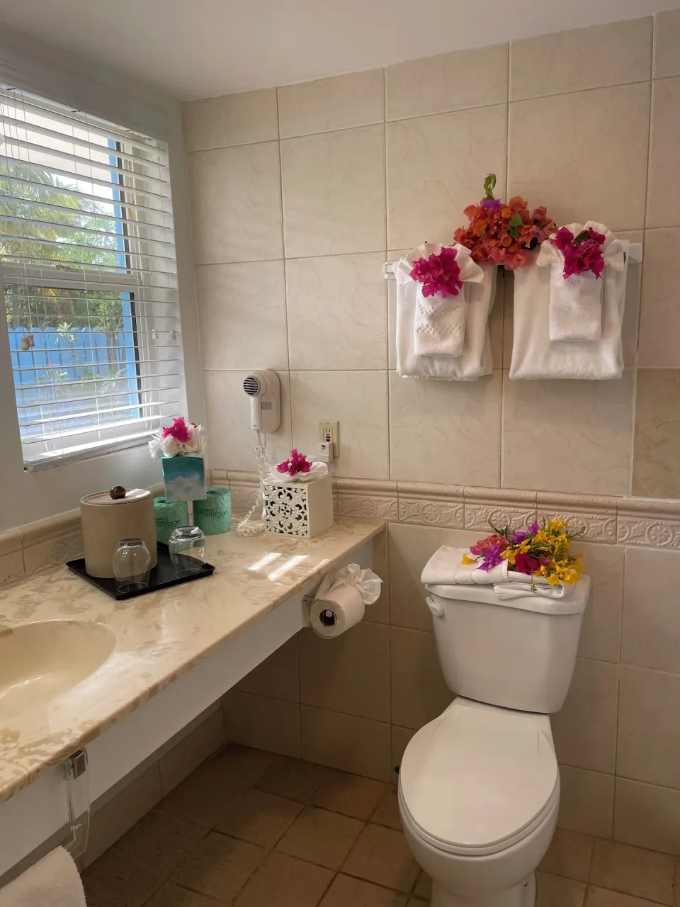 Courtyard View room bathroom with tiled vanity and floral towels at Sibonné Beach Hotel.