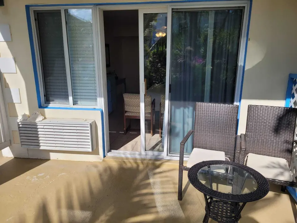 Courtyard View room patio with chairs and sliding doors at Sibonné Beach Hotel.
