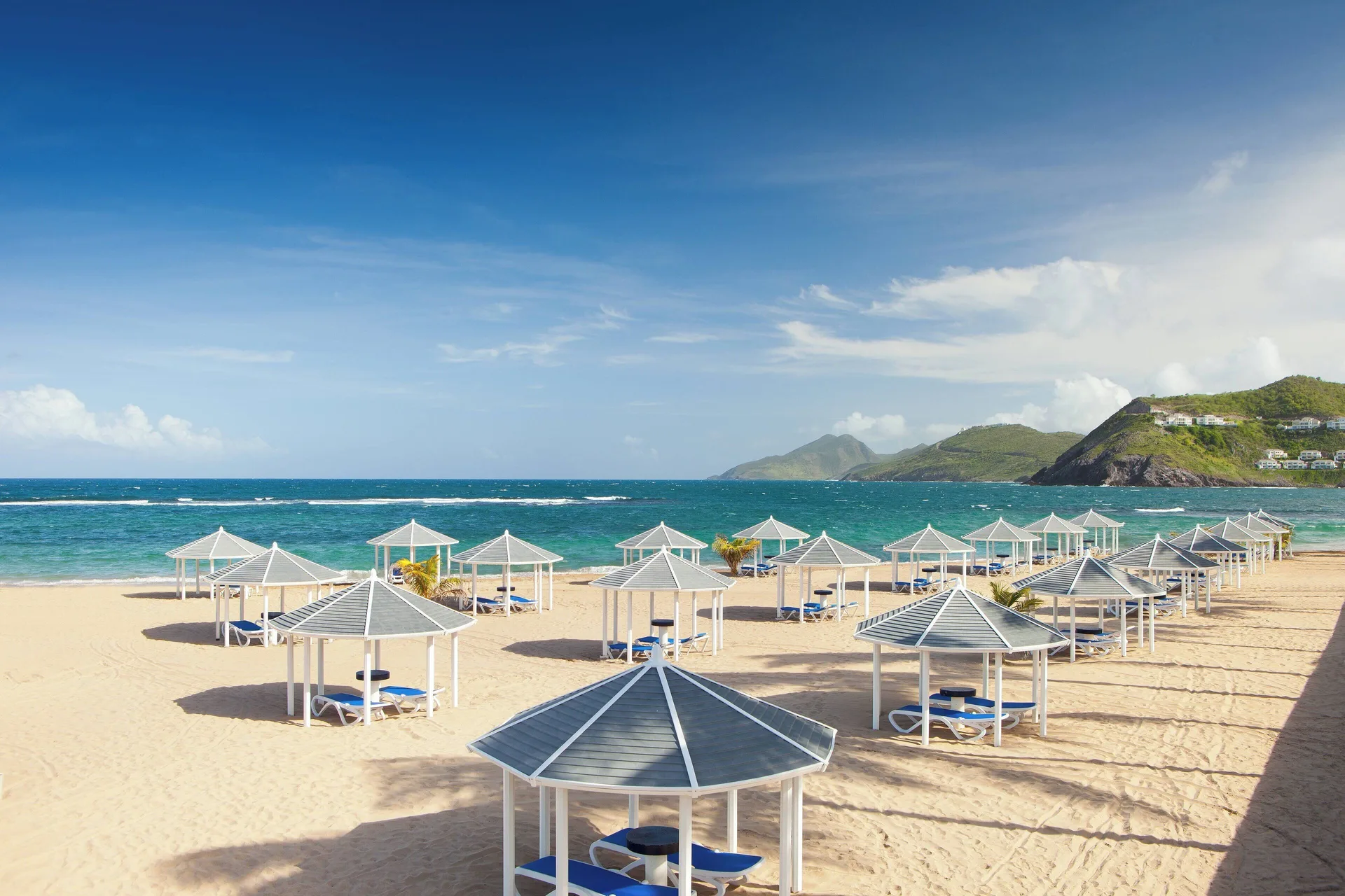 Beach cabanas and lounge chairs on the sand at St Kitts Marriott Beach Resort, Casino & Spa.