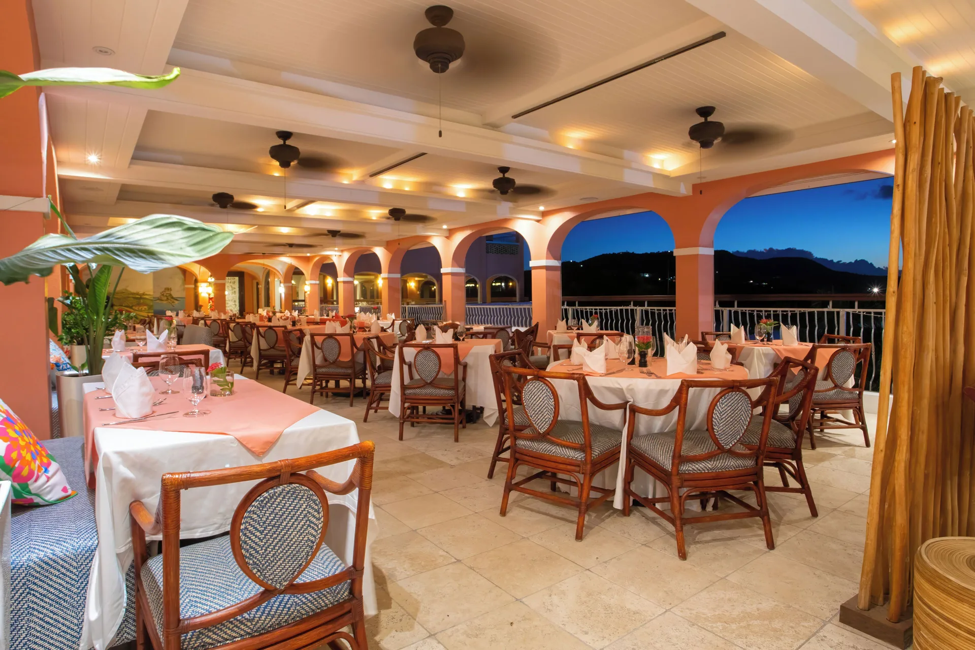 Terrace dining room set for dinner at dusk at The Buccaneer Beach & Golf Resort.