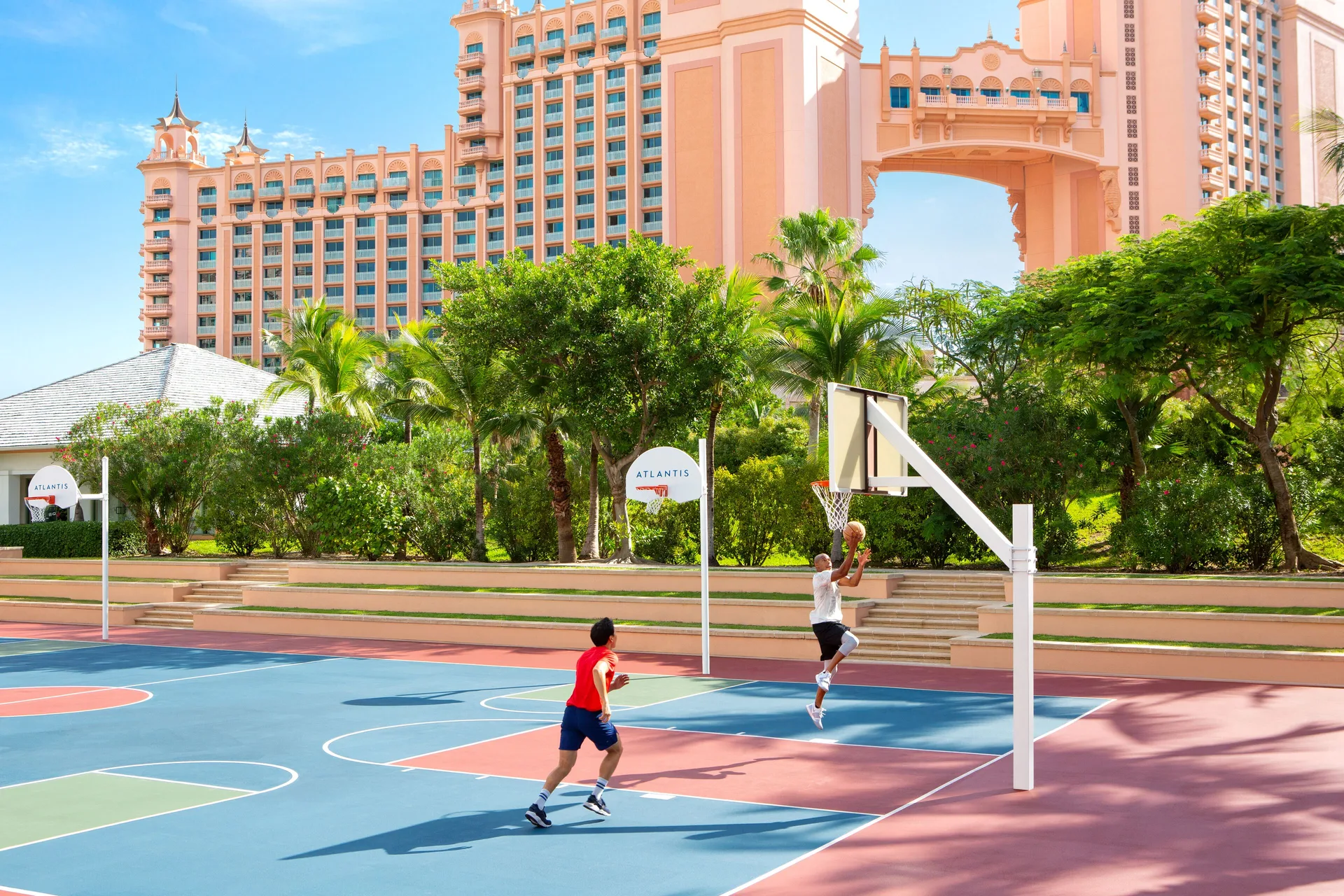 Two people play basketball on an outdoor court at The Coral at Atlantis.
