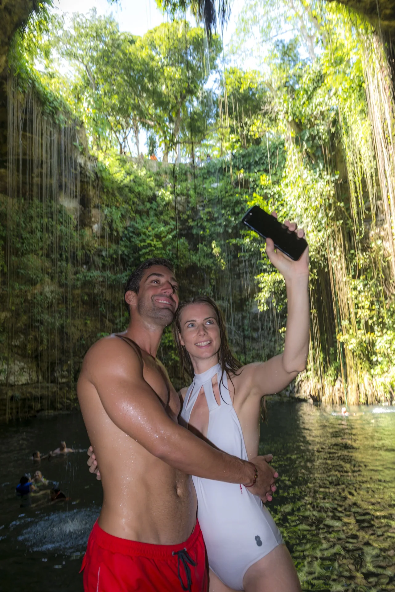 Couple taking a selfie in a leafy cenote near The Fives Oceanfront Riviera Maya.
