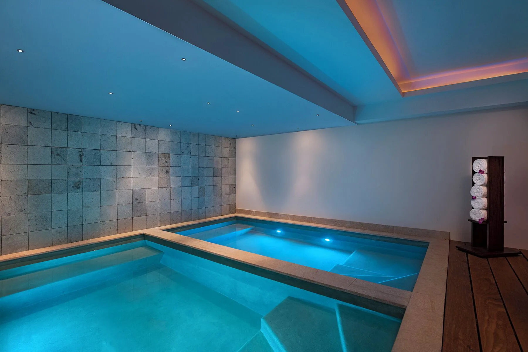 Indoor spa pools with blue lighting and towel rack at The Fives Oceanfront Riviera Maya.
