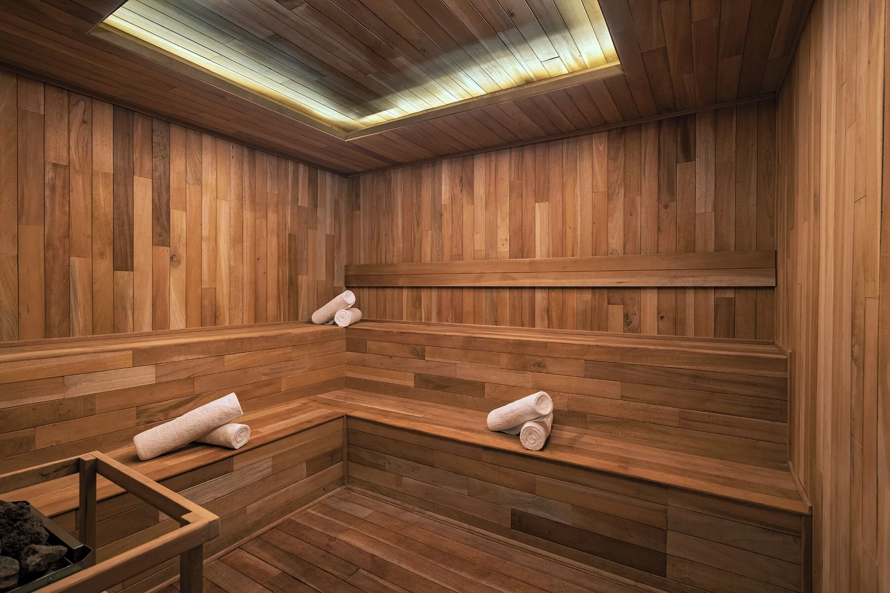 Wood-lined sauna with benches and rolled towels at The Fives Oceanfront Riviera Maya.