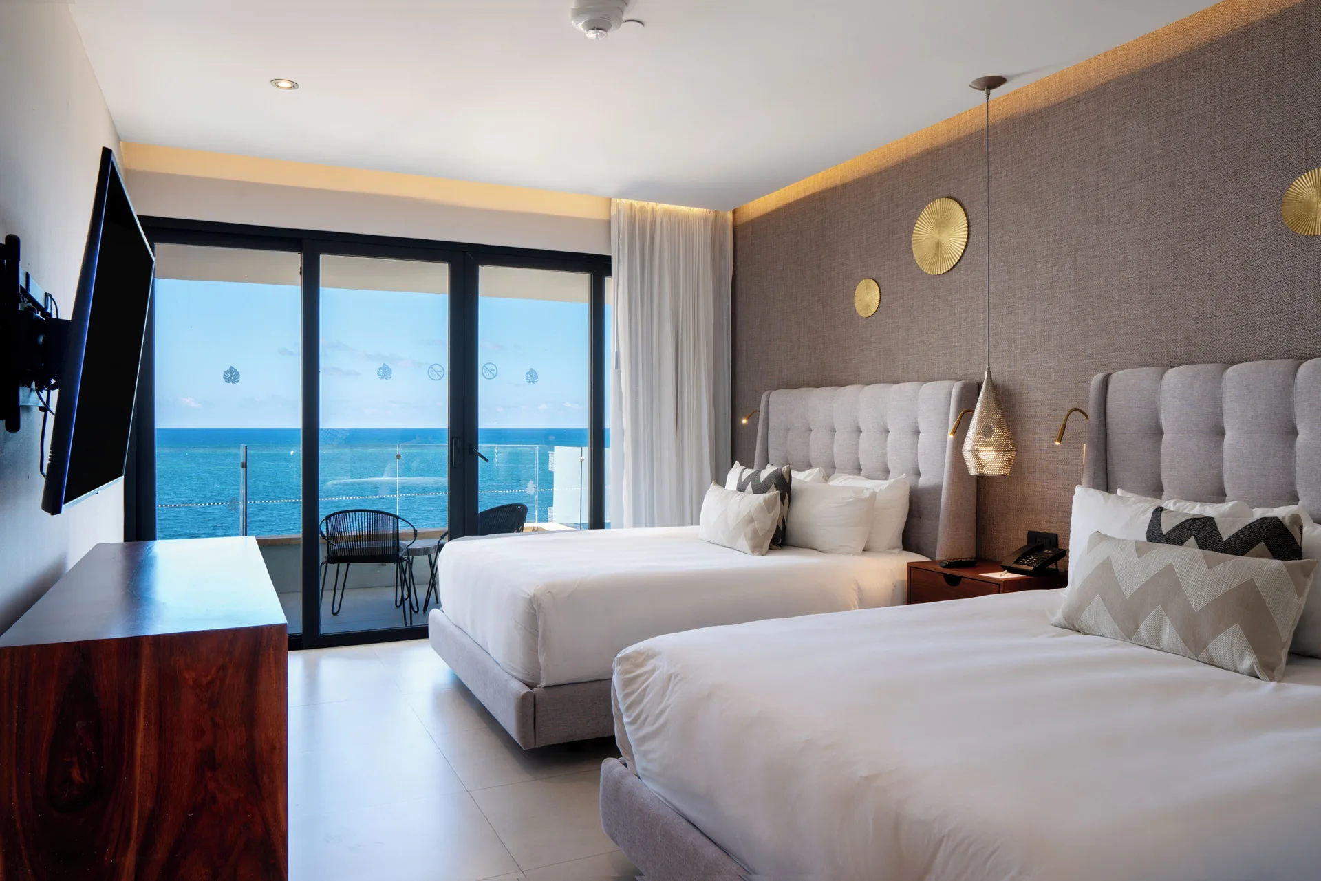 Two-bed ocean-view bedroom with balcony doors at The Fives Oceanfront Riviera Maya.