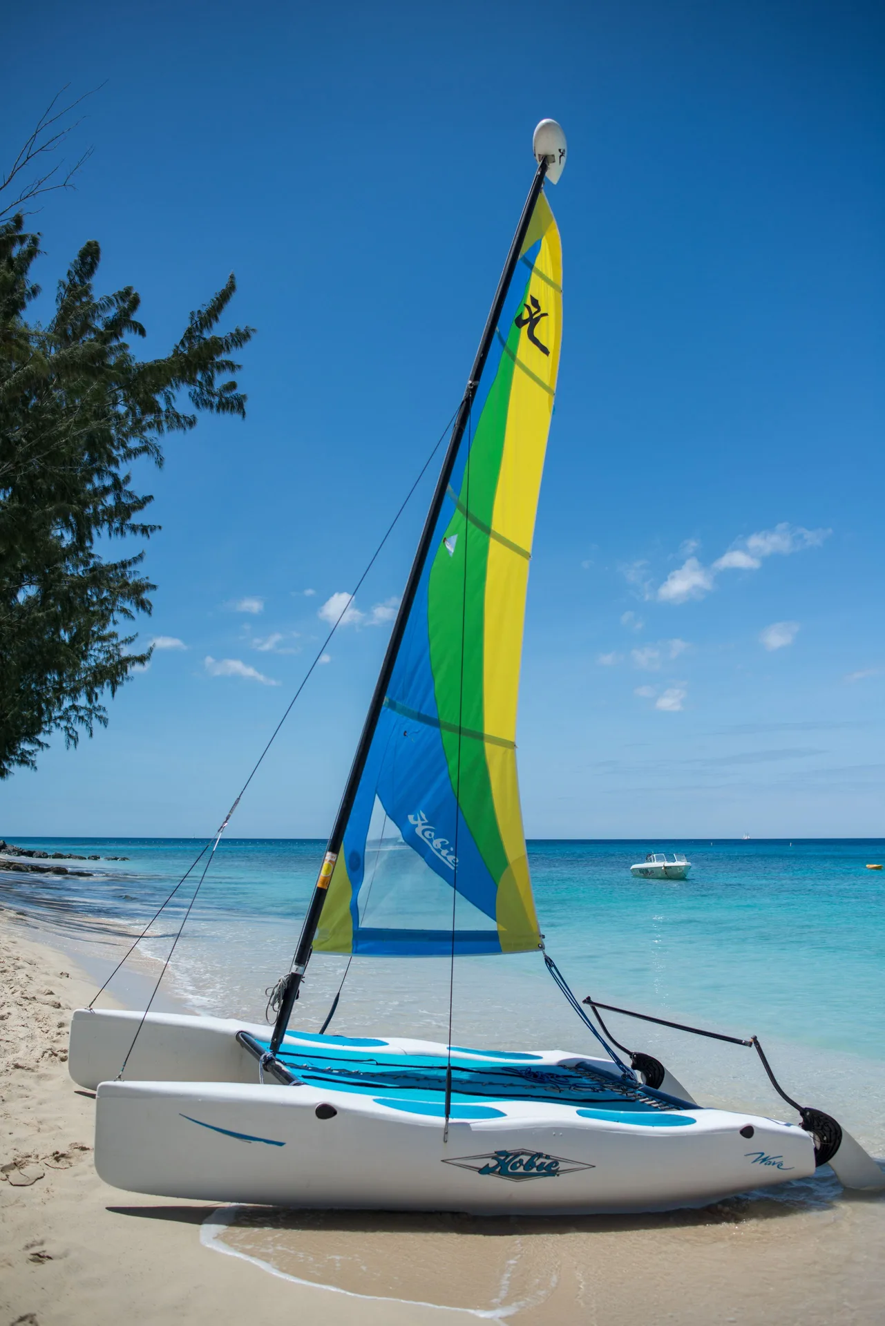 Colorful catamaran pulled onto the sandy beach beside turquoise water at The House.