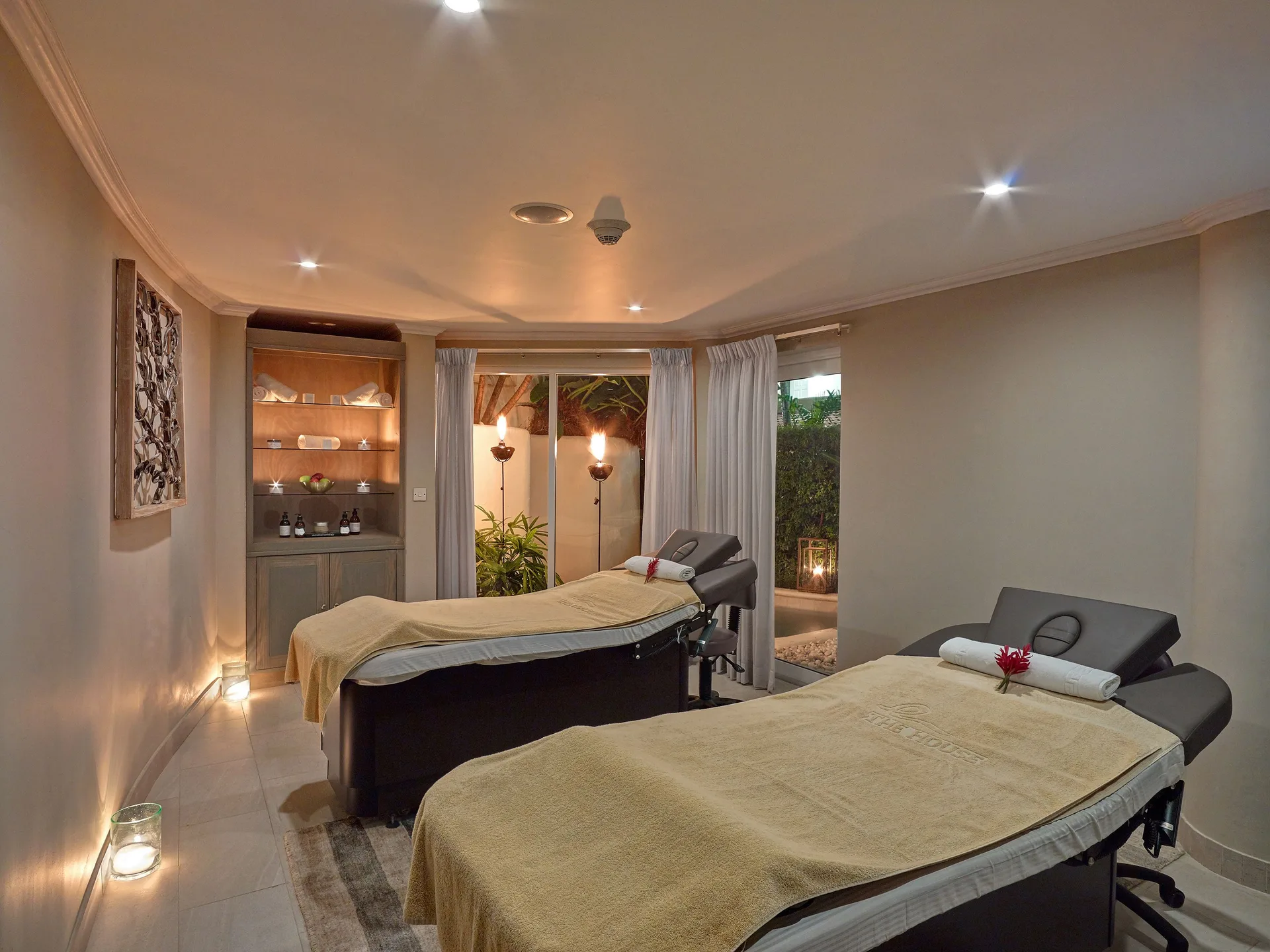 Spa treatment room with two massage tables and soft candlelight at The House.