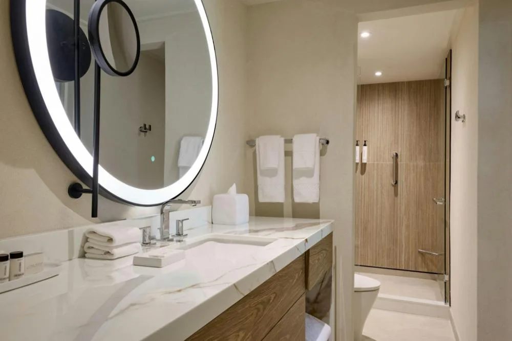 Luxury Garden View bathroom vanity with lit round mirror and shower at The House.