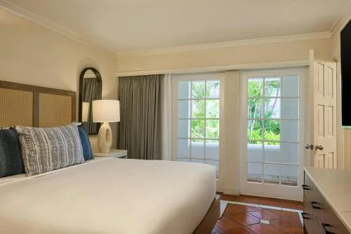 Luxury Garden View bedroom showing king bed, curtains, and leafy doors at The House.