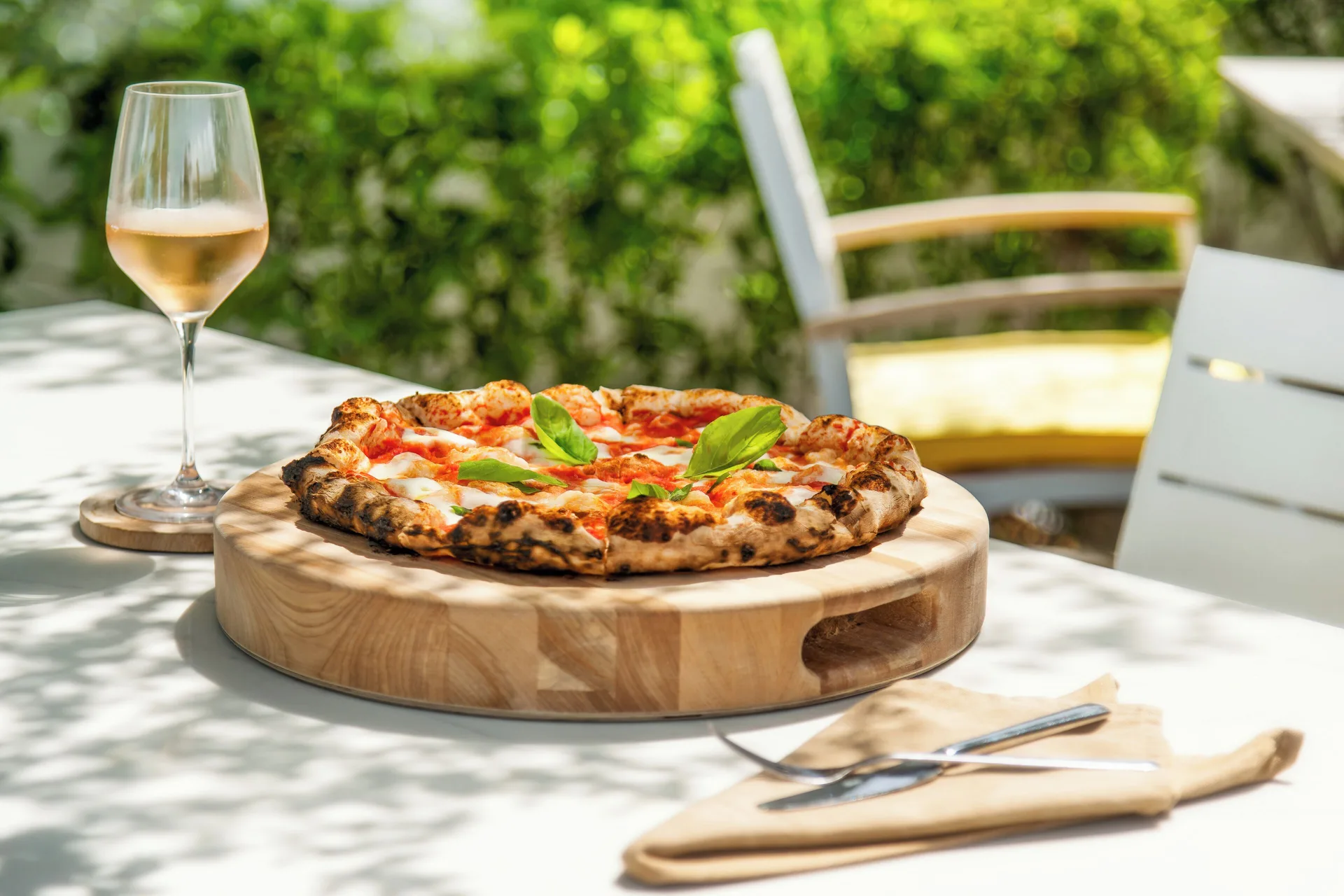 Pizza on a wooden board with a glass of wine at The Oasis at Grace Bay.