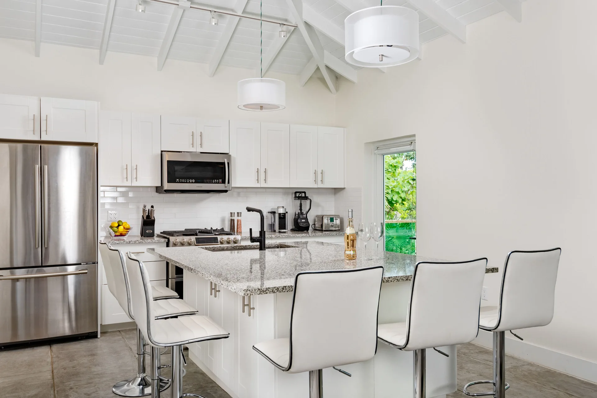 Luxury Villa kitchen with island seating, white cabinets and vaulted ceiling at The Oasis at Grace Bay.
