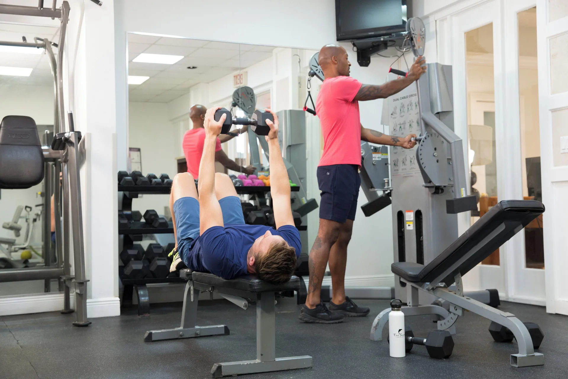 Guests using benches, weights, and cable equipment at The Sands at Grace Bay fitness room.