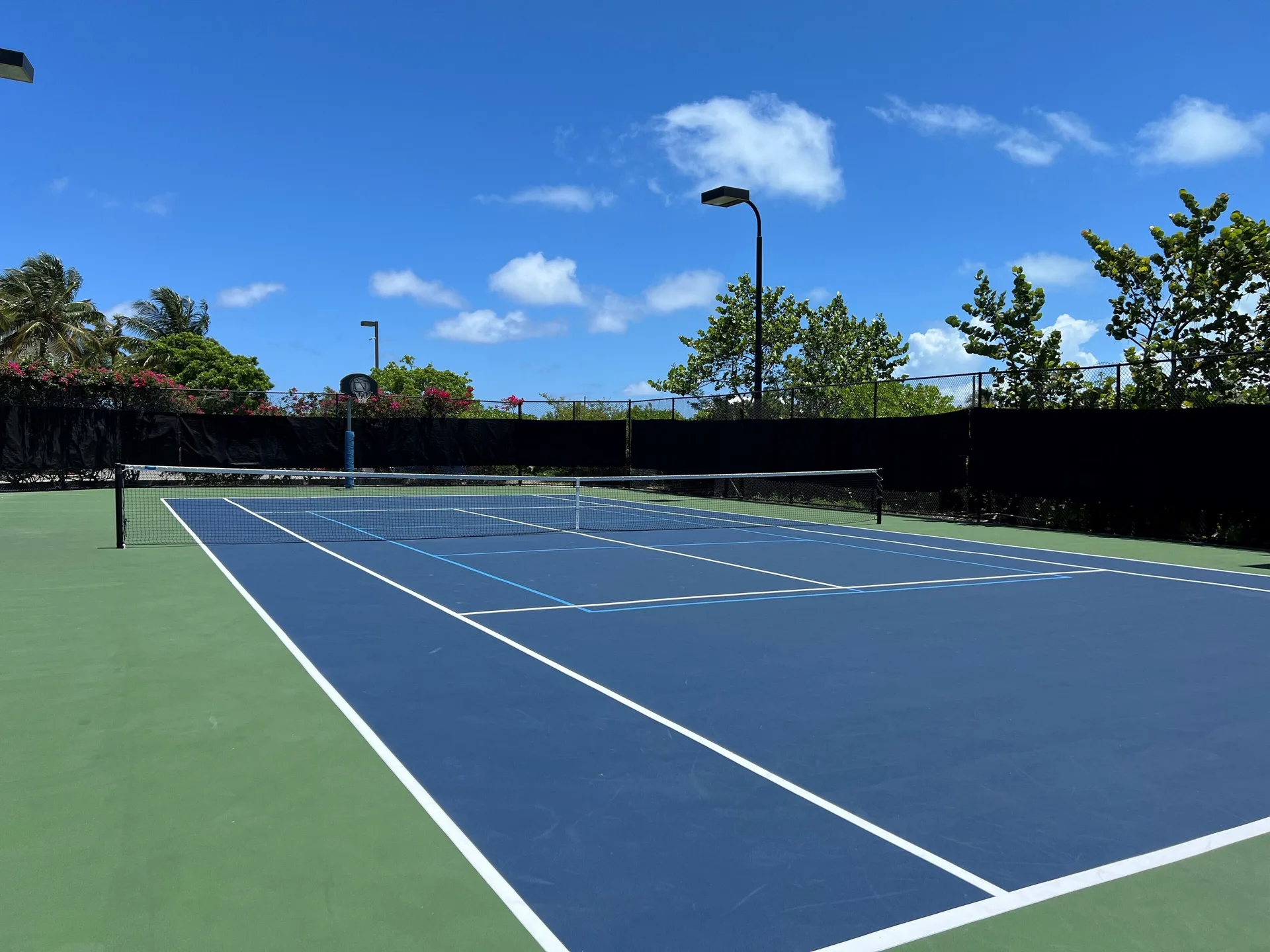 A blue and green tennis court sits under a bright sky at The Sands at Grace Bay.