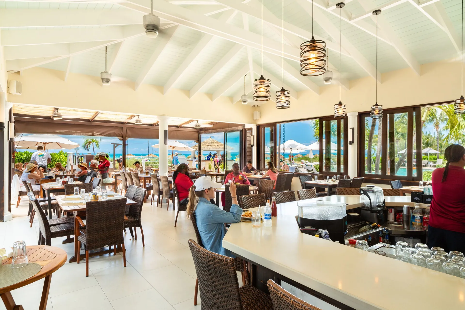 Bright restaurant interior with bar seating and ocean views at The Sands at Grace Bay.