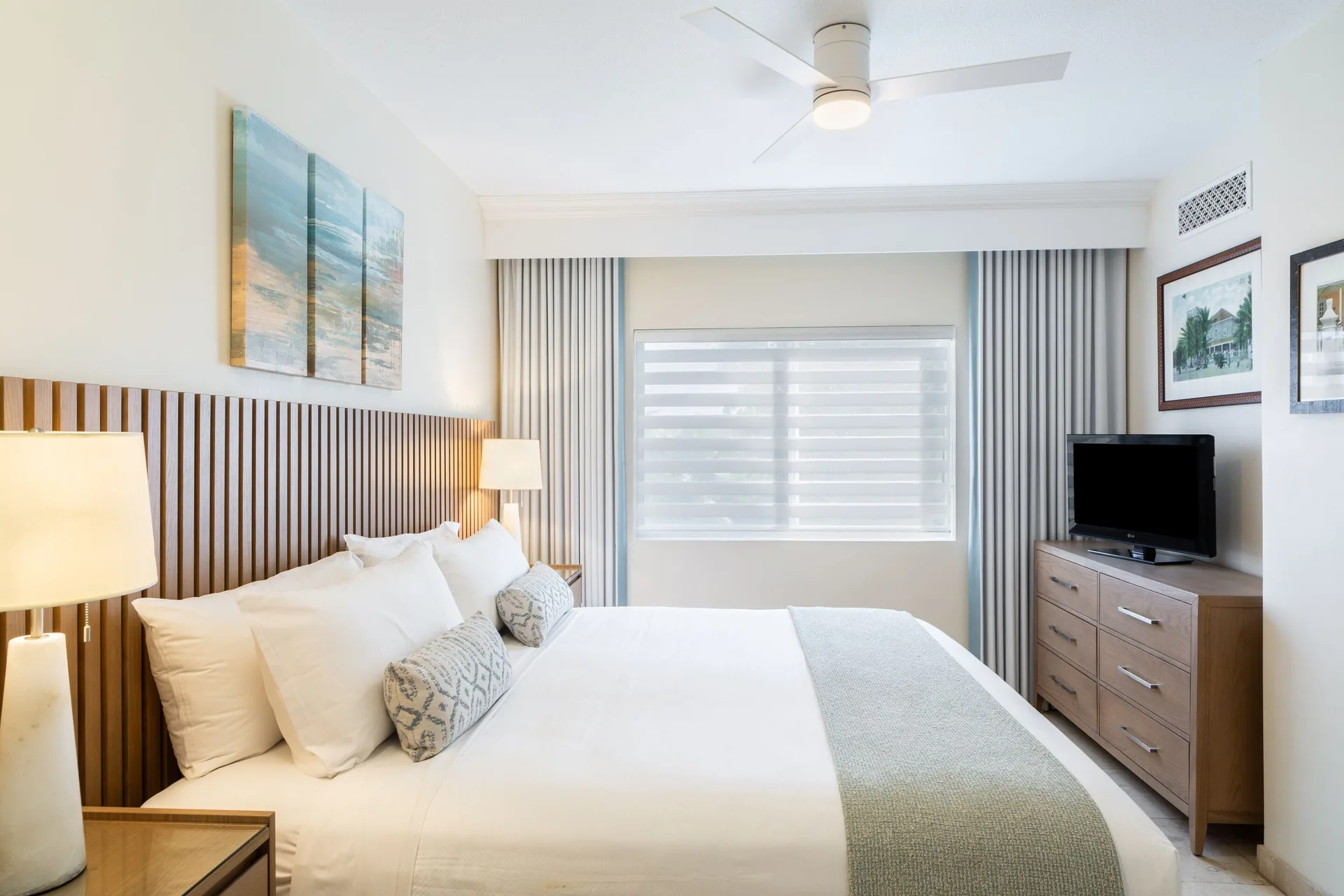 One-bedroom garden view suite bedroom with king bed and dresser TV at The Sands at Grace Bay.
