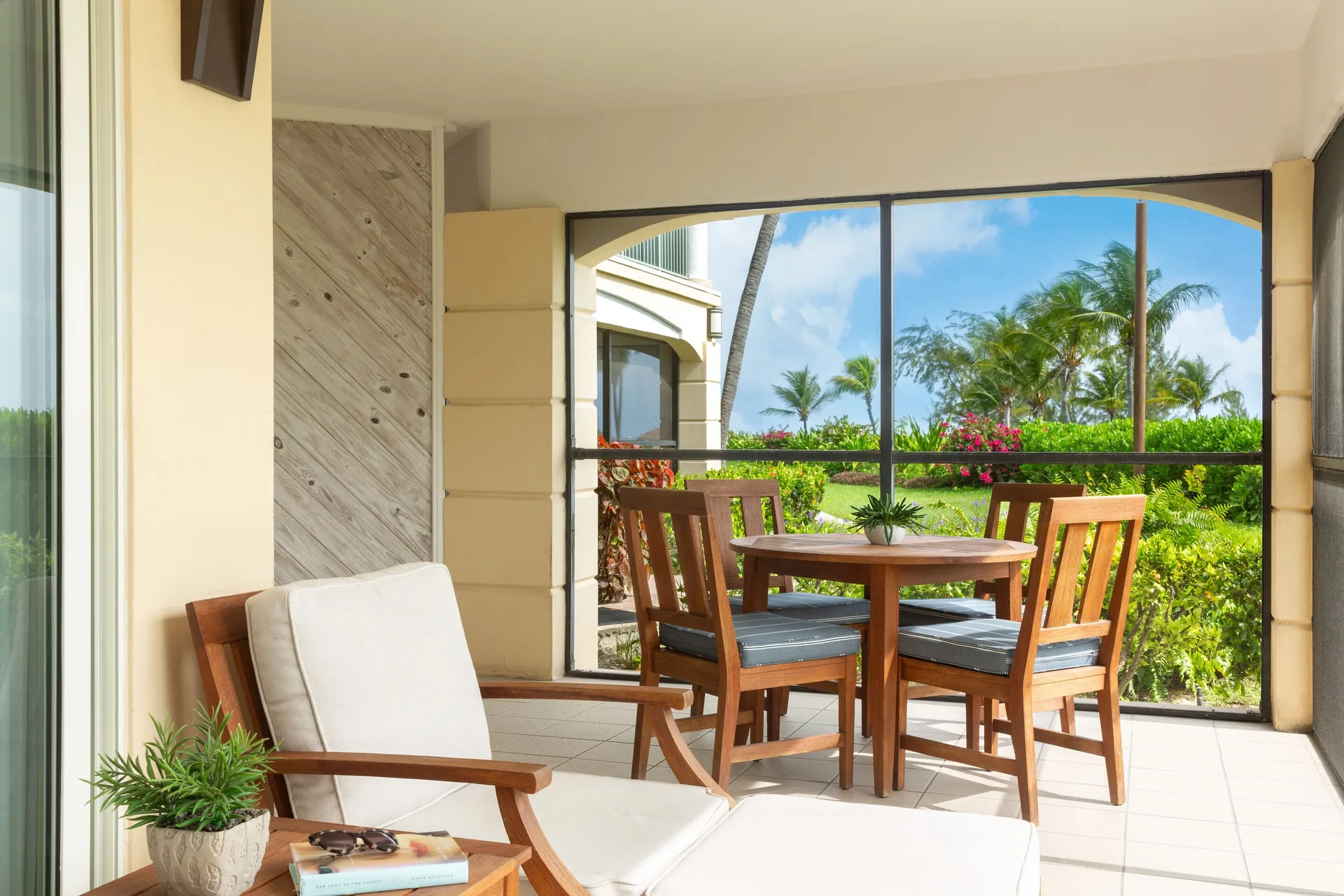 Screened garden patio with lounge chair and dining set at The Sands at Grace Bay.