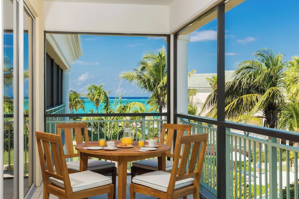 Furnished balcony with ocean and palm views at The Sands at Grace Bay.