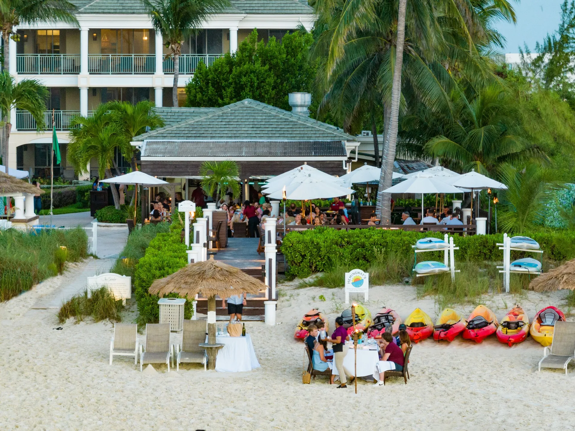 A beach event setup with kayaks and dining areas is shown at The Sands at Grace Bay.