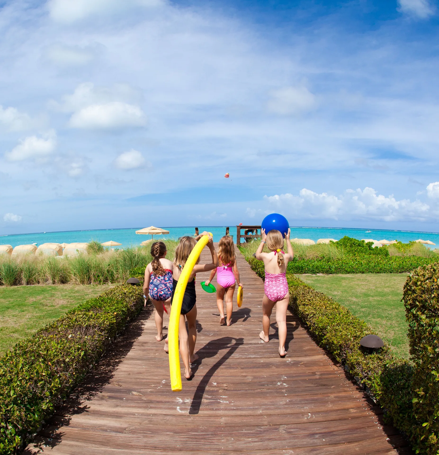 Children carrying pool toys on the beach boardwalk at The Somerset on Grace Bay.