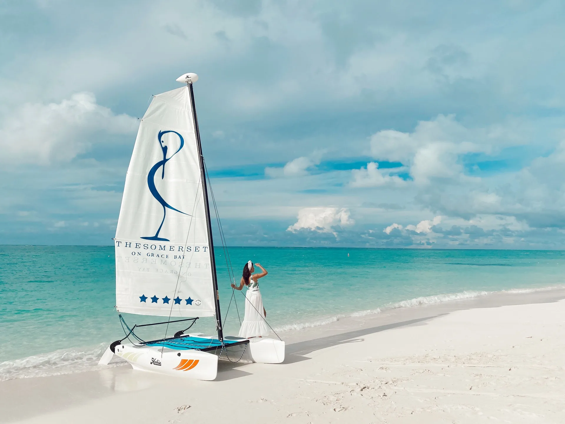 Catamaran sailboat on the beach with The Somerset on Grace Bay logo on the sail.