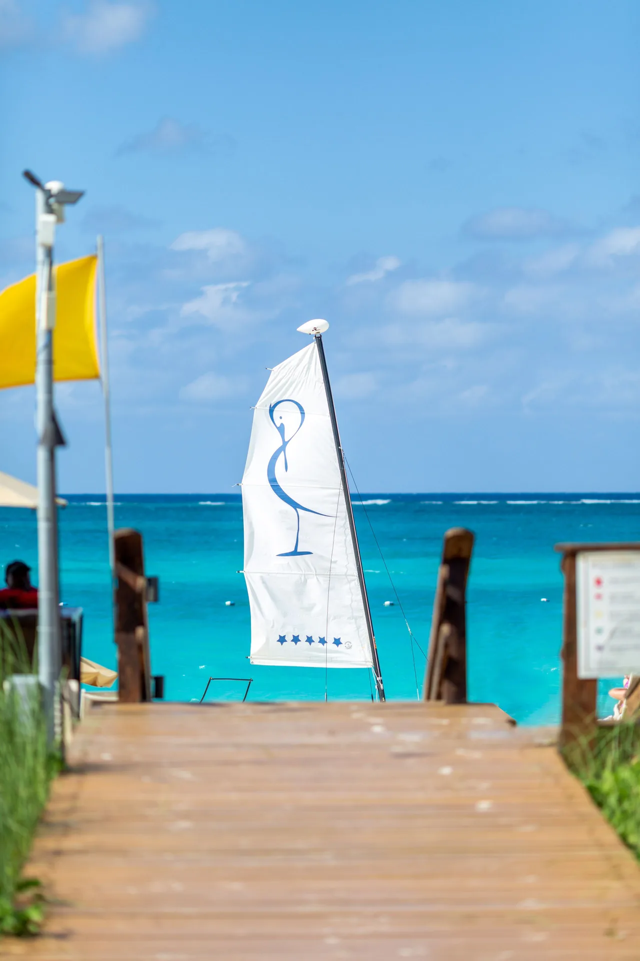 Beach walkway and sailboat on turquoise water at The Somerset on Grace Bay.
