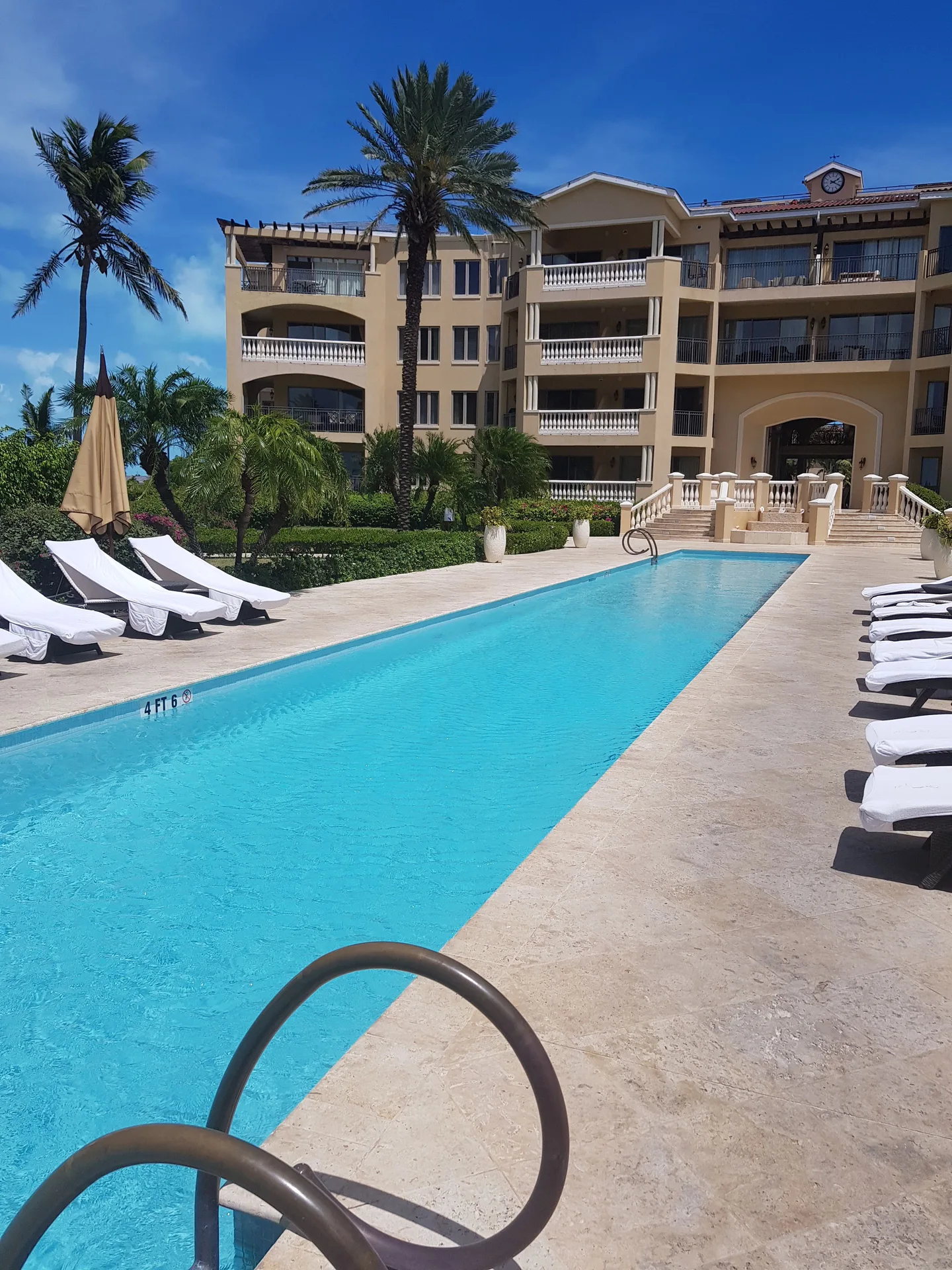 Long pool with white loungers, palms, and balconies at The Somerset on Grace Bay.